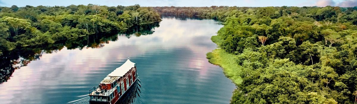 River cruise ship sailing along the Amazon River through tropical rainforest scenery
