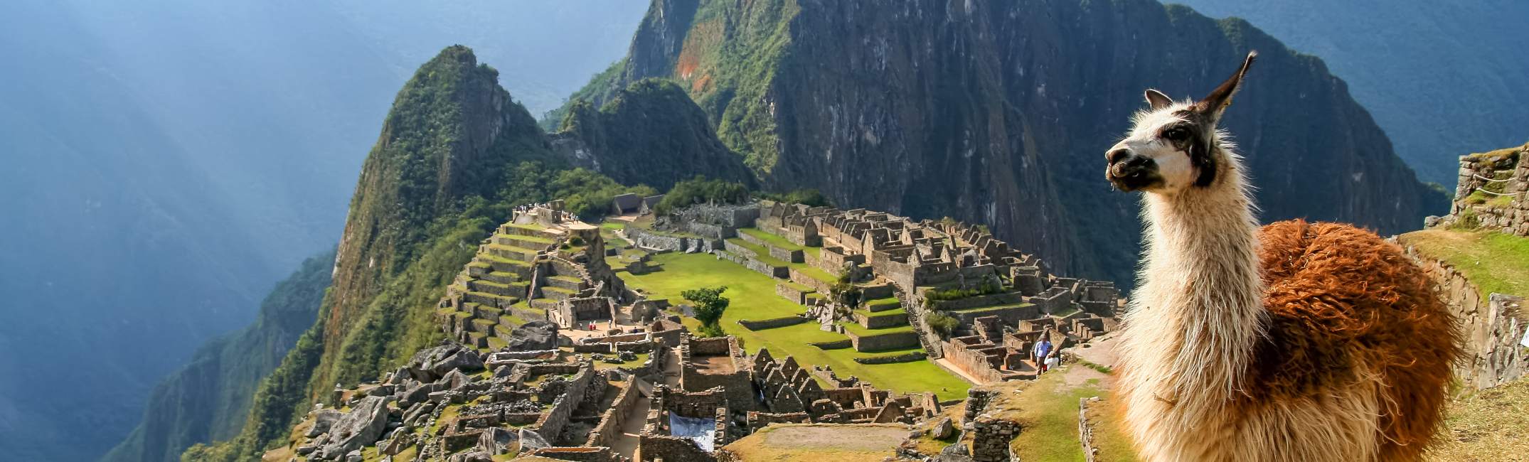 Peru river cruises featuring Machu Picchu in the Andes Mountains, with ancient Inca ruins surrounded by dramatic peaks and cloud-covered scenery in Peru.