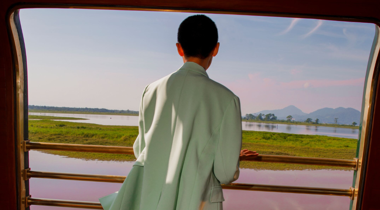 A smart-casual traveller relaxing and looking out the window at the Malaysian countryside.