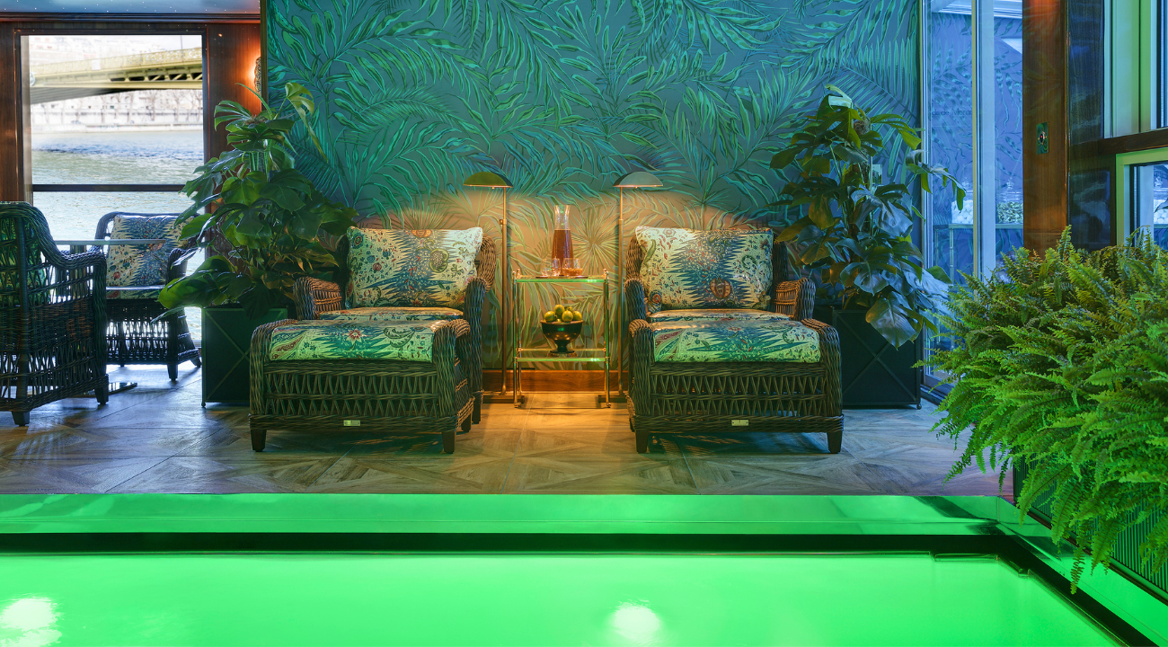 The luxury indoor pool at Le Club L’Esprit onboard the S.S. Joie de Vivre with a view through the glass windows.