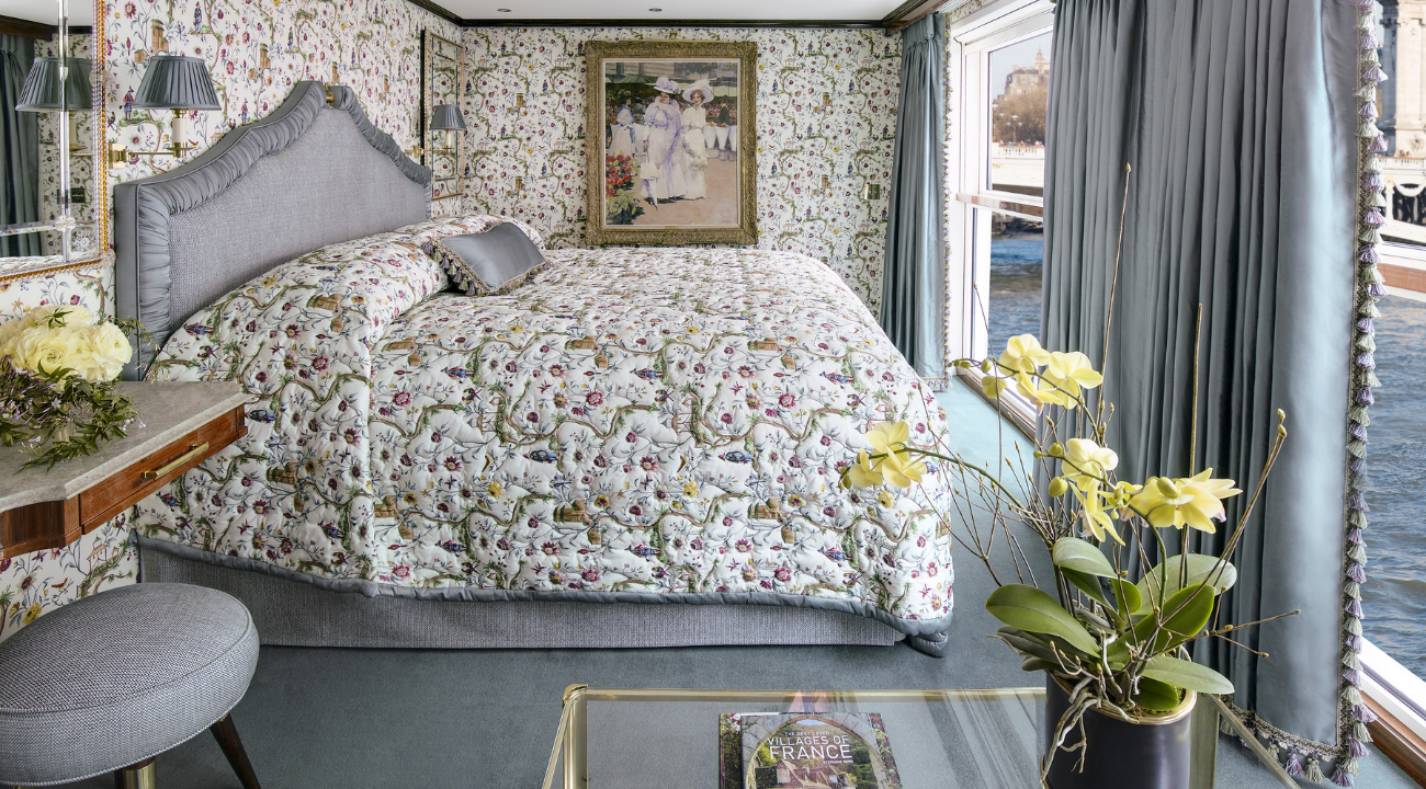 A luxurious stateroom interior on the S.S. Joie de Vivre featuring elegant French fabrics and a comfortable queen-sized bed.