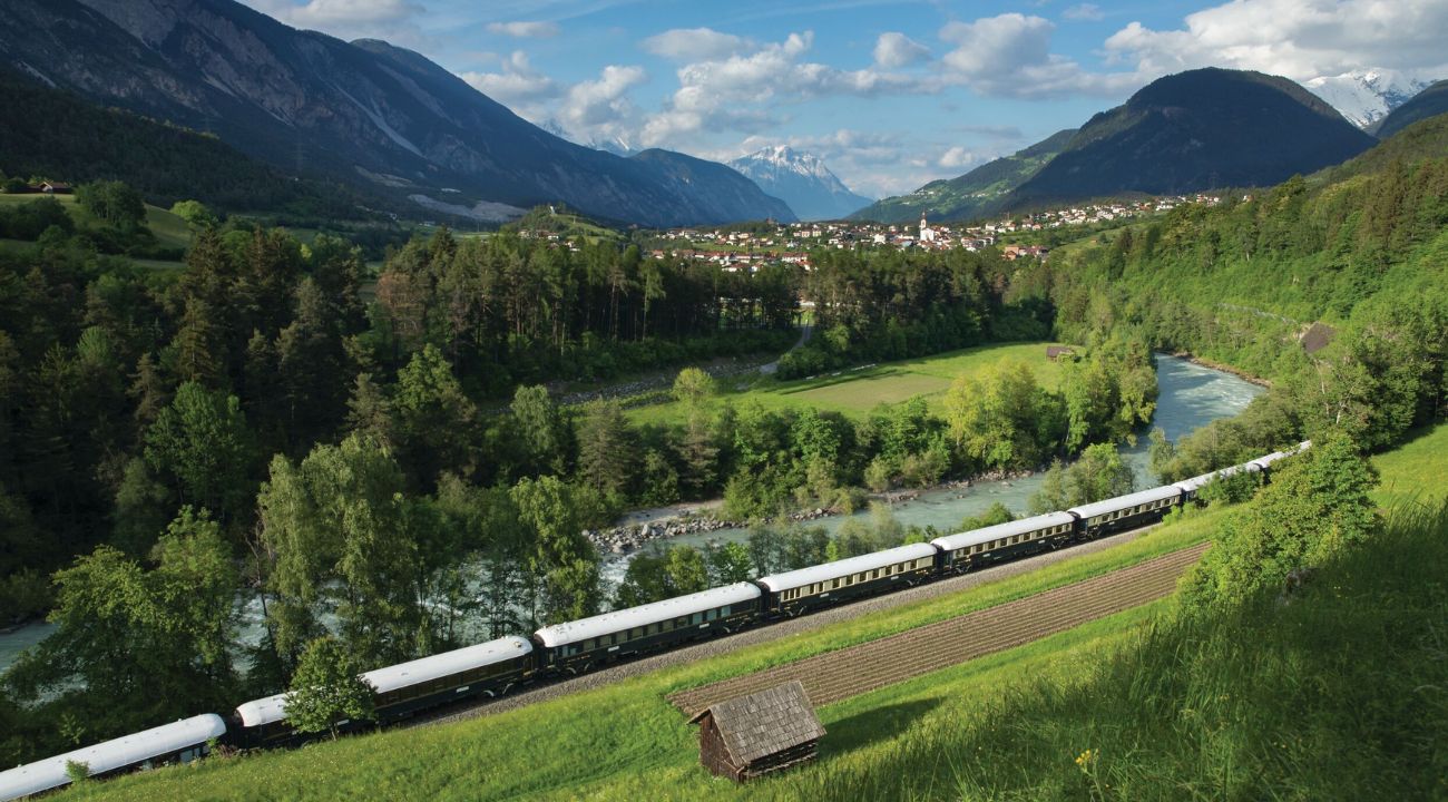 Venice Simplon-Orient-Express train travelling through the Alps with scenic mountain views. One of the Best Easter holiday destinations in Europe.