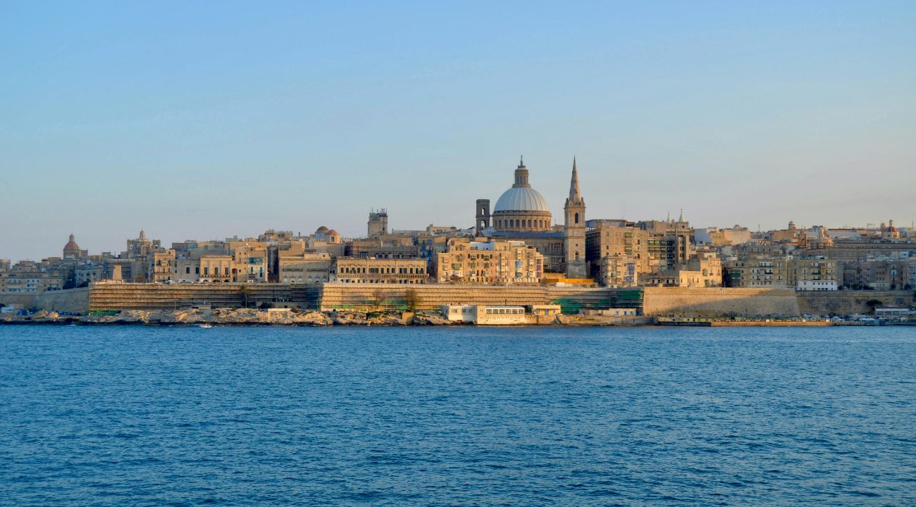 View of Malta’s coastline from the sea with historic buildings and clear blue water. One of the Best Easter holiday destinations in Europe.
