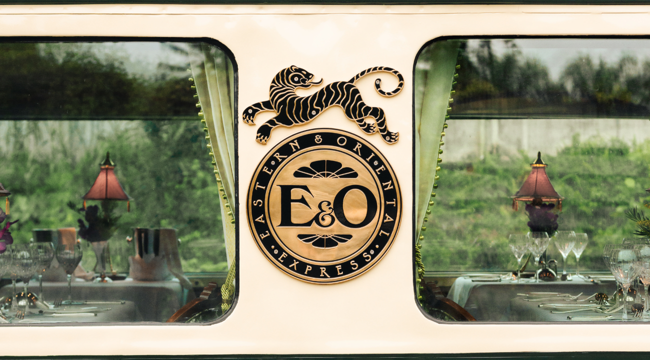 Golden crest logo of the Eastern & Oriental Express train on a green background.