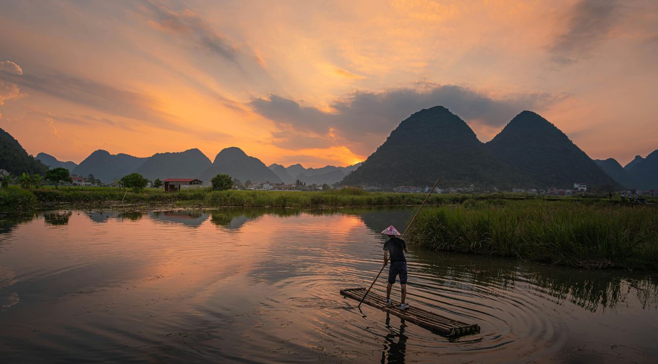 Bamboo rafting at sunset in rural Asia, a unique cultural touring holiday experience