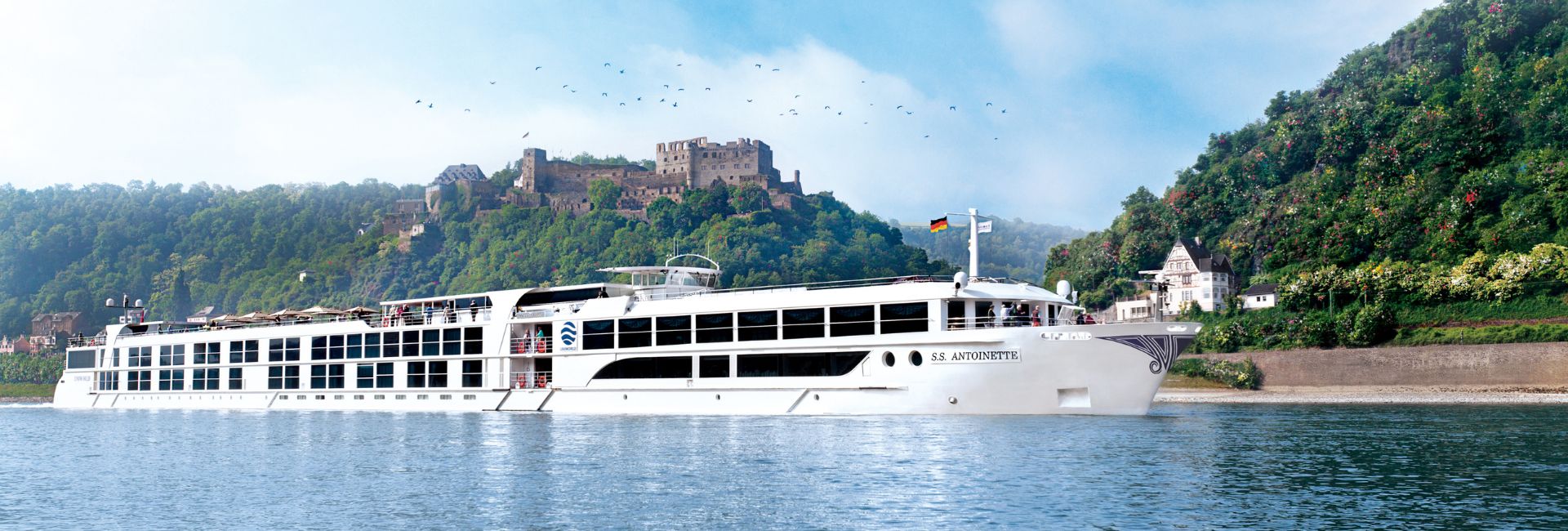 River cruise ship sailing on the Rhine River passing a medieval castle in Germany
